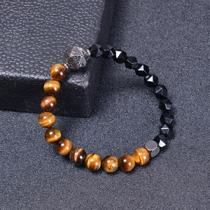 Detail of tiger eye beads and faceted black stones with a textured metal bead on a bracelet