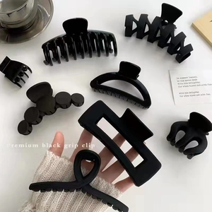 Détail de diverses pinces à cheveux noires mates et brillantes sur un bureau minimaliste