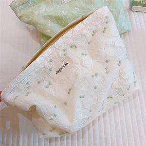 Close-up of green cherry floral jacquard texture and metal zipper on makeup bag