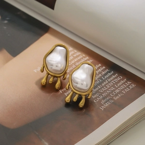 Elegant gold molten lava earrings with irregular baroque pearls on a fashion magazine