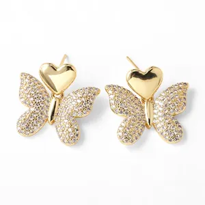 Detalle de pendientes de mariposa dorados con cristales brillantes y forma de corazón