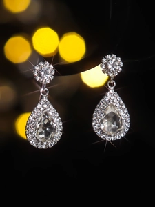 Macro shot of silver teardrop earrings with sparkling rhinestones and halo setting detail