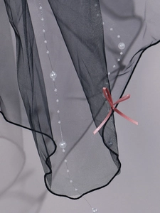 Detail of black tulle bridal veil featuring white pearls and elegant pink silk bows