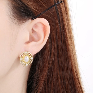 Detail view of vintage pearl stud earring with rhinestones on golden metal base