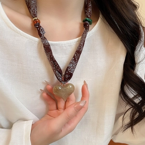 Detail of paisley fabric cord and marble texture heart pendant on a woman's neck