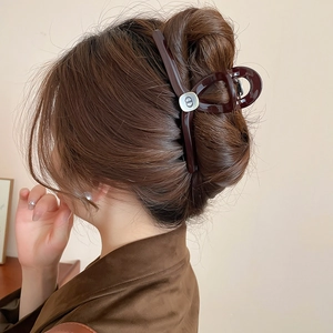 Detail view of a vintage dark brown hair claw clip with CD metal logo on hair