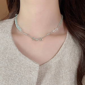 Detail of layered beaded necklace with light blue faceted stones and silver beads on neck