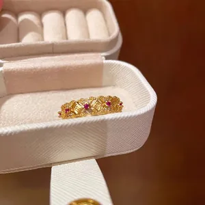 Detail of vintage gold bamboo ring with red gemstones in a white jewelry box