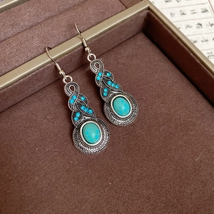 Detailed close-up of vintage hollow leaf earrings with turquoise stones and blue rhinestones
