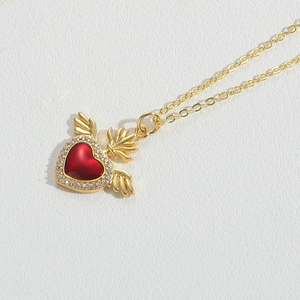 Detail of gold-plated wing pendant with red zircon heart and micro-paved crystals