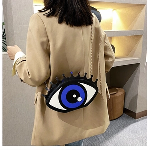 Detail of creative evil eye chain bag with crown trim on khaki blazer background