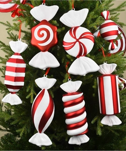 Close-up of red and white spiral candy ornaments hanging on a green Christmas tree branch
