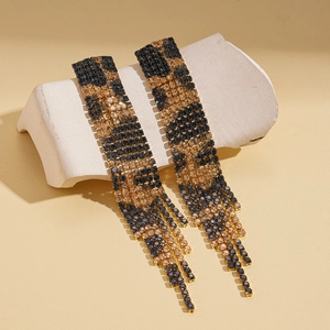 Macro detail of luxury leopard print tassel earrings with sparkling rhinestones in gold setting