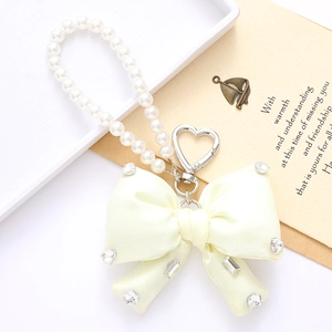 Detail of elegant satin bow keychain with sparkling rhinestones and white pearls