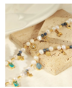 Gros plan détaillé du collier doré avec pierres naturelles, perles et breloques géométriques