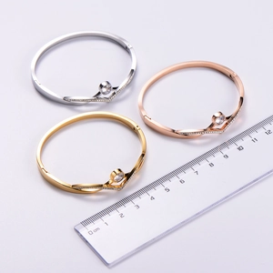 Detailed top view of gold, silver, and rose gold V-shaped bracelets with central rhinestone