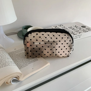 Detailed view of heart-print mesh cosmetic bag featuring a secure black zipper closure