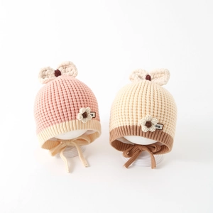 Detail of knitted baby winter hats featuring cute bow decor and floral accents with ear flaps