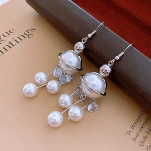 Vue macro de boucles d'oreilles Saturne argentées avec pompons en perles et strass brillants