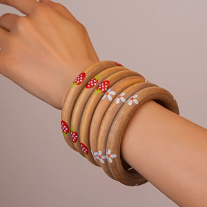 Detail view of stacked wooden bangles with hand-painted strawberry and daisy floral patterns