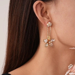 Detail of floral drop earrings with zircon crystals and faux pearls on model