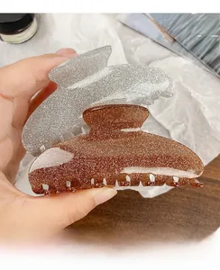 Detailed macro view of large glittery acrylic hair claws in silver and amber brown colors