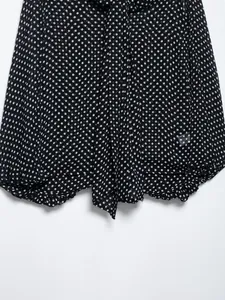 Detail of black polka dot chiffon shirt with delicate bow tie and ruffled hem finish