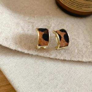 Macro shot of faux calf hair leopard print earrings with elegant gold metal trim