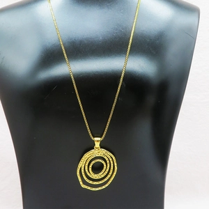 Detail of a layered golden irregular circle pendant necklace on a black mannequin display
