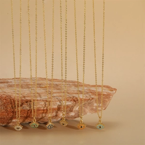 Golden evil eye necklaces with colorful zircon stones hanging over a red stone block