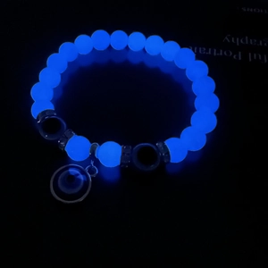 Glow-in-the-dark evil eye beaded bracelet with bright blue luminous stones in dark setting