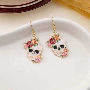 Detailed close-up of skull and flower enamel earrings on a white ceramic display tray