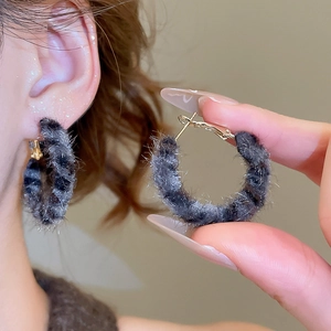 Detail of plush grey leopard print hoop earrings with gold pins and soft furry texture