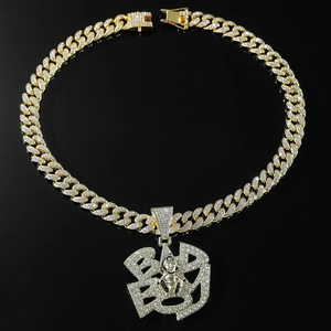 Detail of gold Cuban chain necklace with iced-out BAD BOY letter pendant and human motif