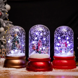 Three musical Christmas snow globes with Santa and snowman on snowy wooden desk