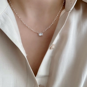 Close-up of minimalist paperclip chain necklace with emerald-cut white zircon pendant
