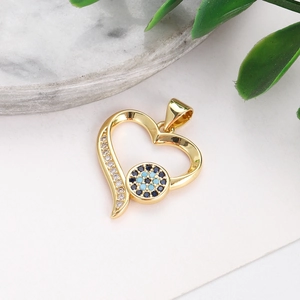 Macro view of gold-plated heart pendant with evil eye motif and colorful crystals