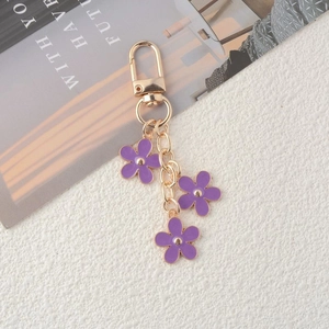 Detail shot of golden keychain with three purple enamel flowers and lobster clasp hook