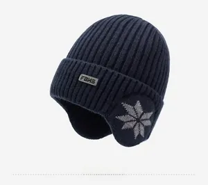 Detailed close-up of a navy blue knitted winter hat featuring earflaps and a snowflake pattern