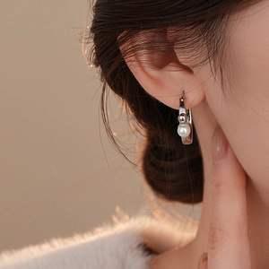 Vue détaillée de l'élégante créole plaquée or 14K avec perle sur l'oreille du mannequin