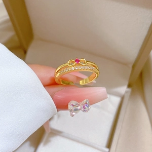 Adjustable gold bow ring featuring red gemstone and micro-set white zircon on a model's hand