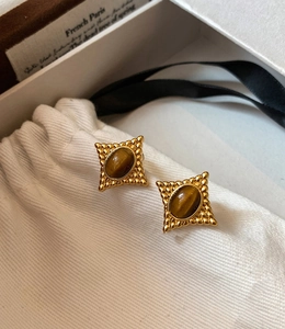 Gros plan sur les boucles d'oreilles vintage avec pierre œil de tigre et métal doré