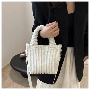 Detail view of white corduroy bucket bag texture with soft handle and metal shoulder strap