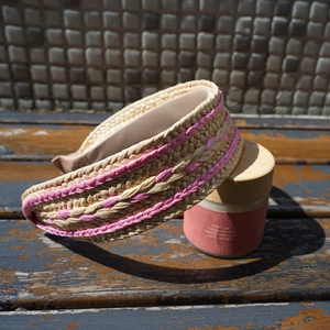 Detailed close-up of straw woven headband with pink trim accents on wooden background