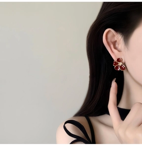 Gros plan de boucles d'oreilles fleurs rouges élégantes plaquées or 18K sur un mannequin