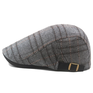 Detail of grey plaid beret with adjustable gold buckle and black visor brim