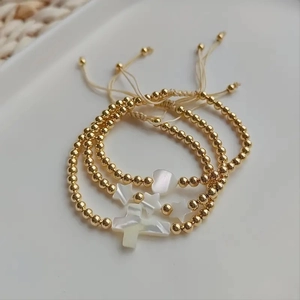 Three-piece gold beaded bracelet set with shell cross, star, and heart charms