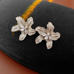 Nahaufnahme glitzernder Blumenohrstecker aus Silber mit Zirkonia auf schwarzem Samt