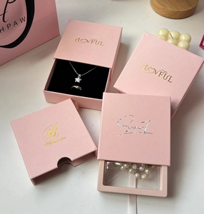Cajas de joyería rosa con logo dorado que muestran collares y anillos para regalo