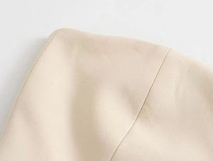 Macro shot of beige suit fabric showing high-density plain weave and precise stitching
